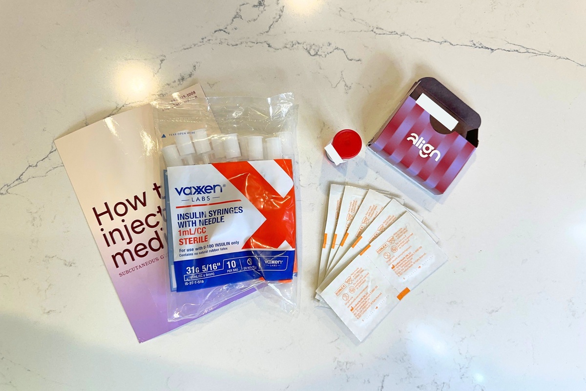 Amble medication vial next to the box it came in, a pack of extra sharps, an instruction sheet, and alcohol wipes
