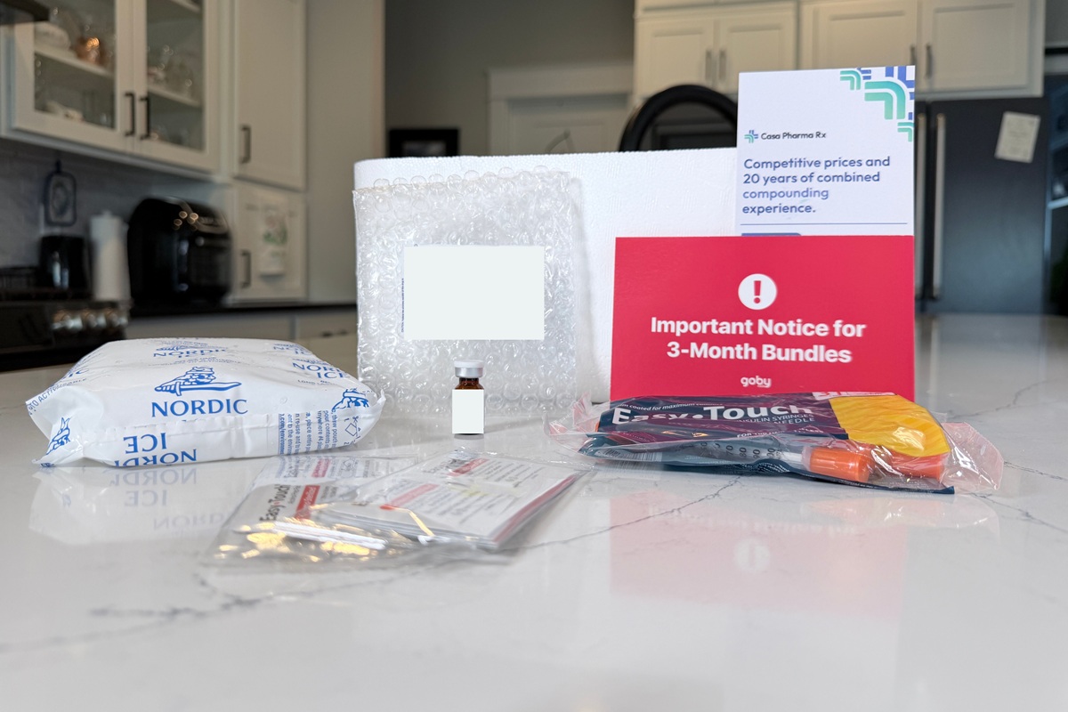 GobyMeds medication vial next to a large ice pack that kept it cool during transportation, a pack of extra sharps, alcohol wipes, injection instruction sheets, and a package