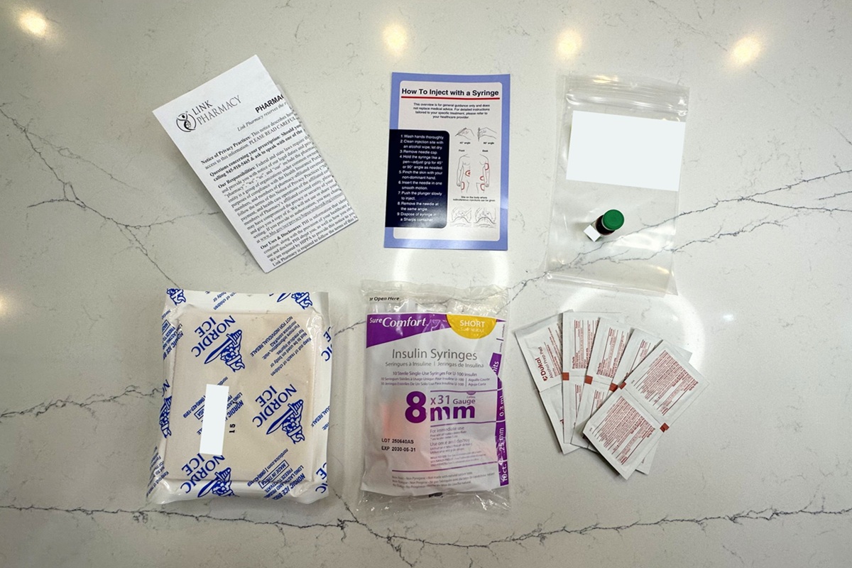 MEDVi medication vial next to two instruction sheets, a large ice pack, a pack of extra sharps, and alcohol wipes